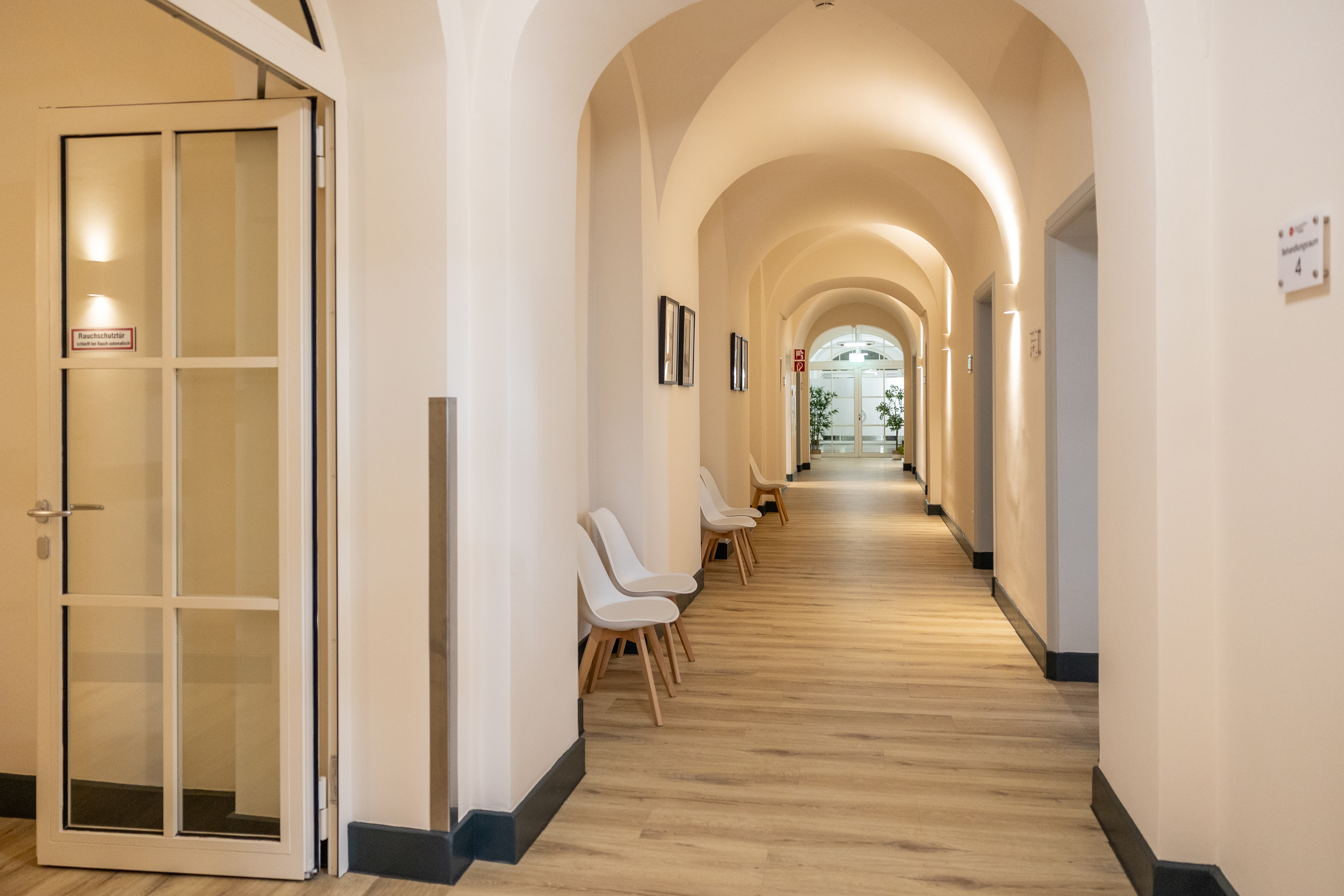 Ein heller Flur mit weißen Wänden, Holzfußboden und modernen Stühlen