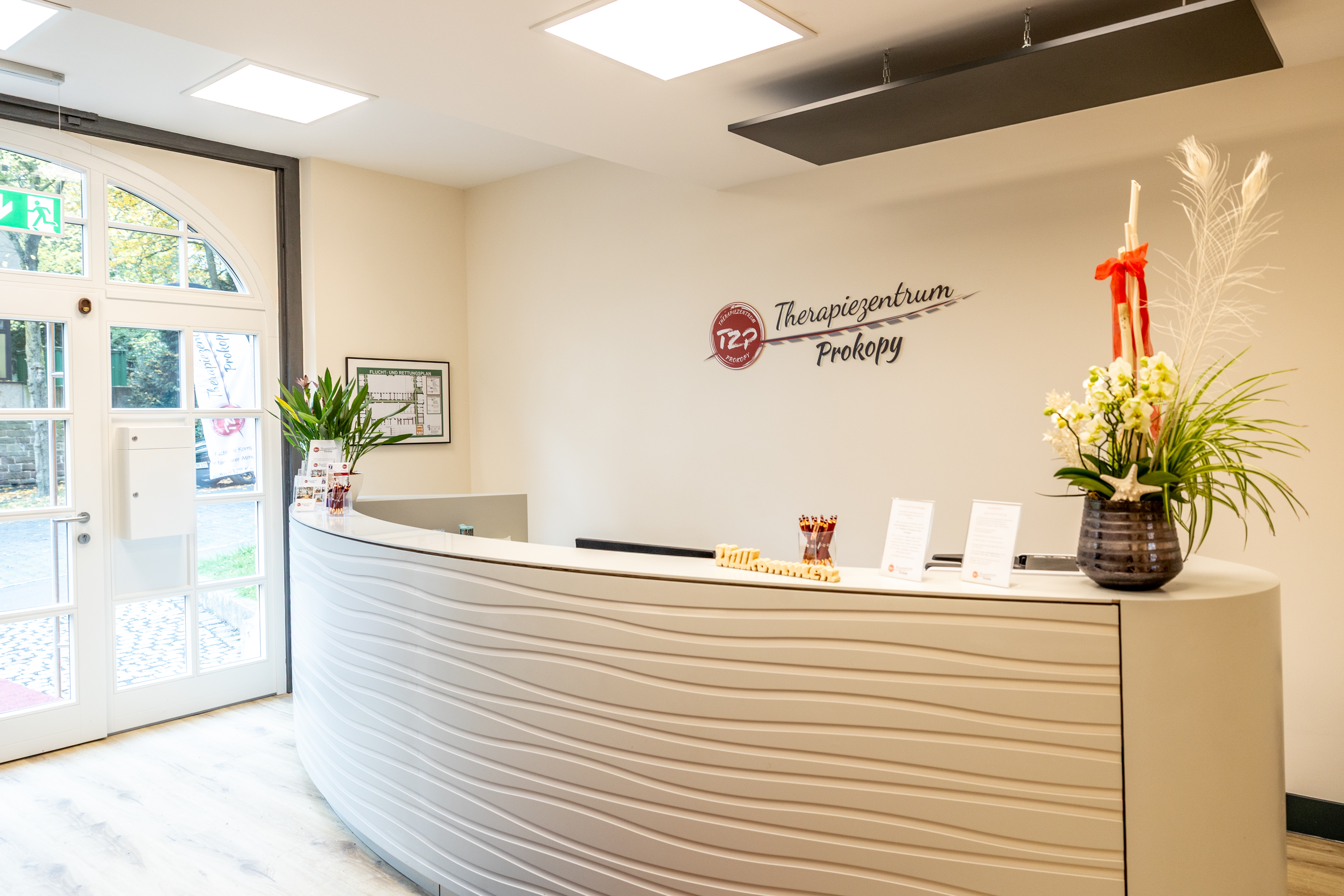 Heller Empfangsbereich mit modernem Tresen, Blumen und freundlicher Atmosphäre