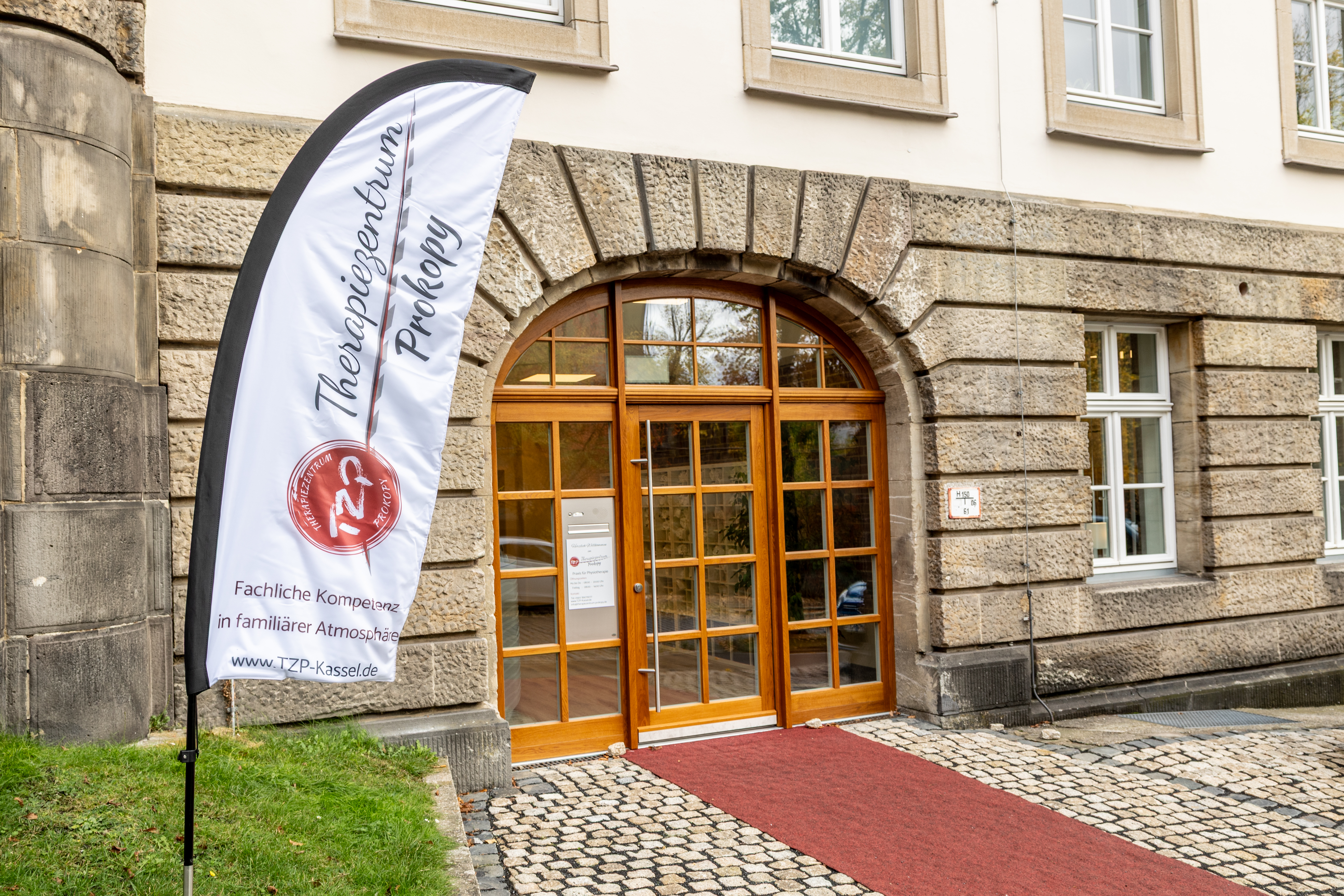 Ein Gebäude mit steinernen Wänden, Glasfenster und rotem Teppich vor dem Eingang